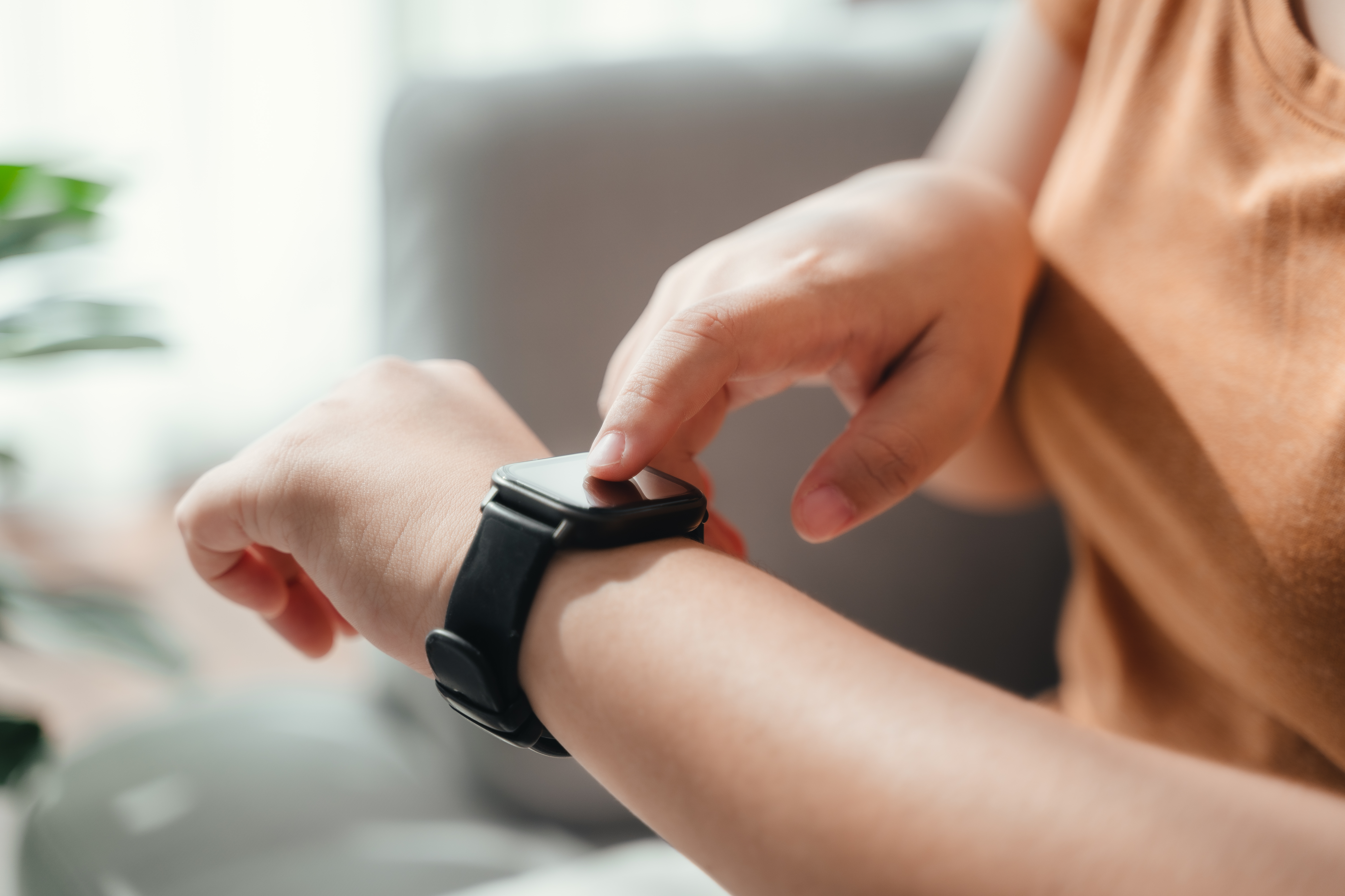 young woman looking and using a smartwatch, Female sitting on th Best Home Monitoring Devices